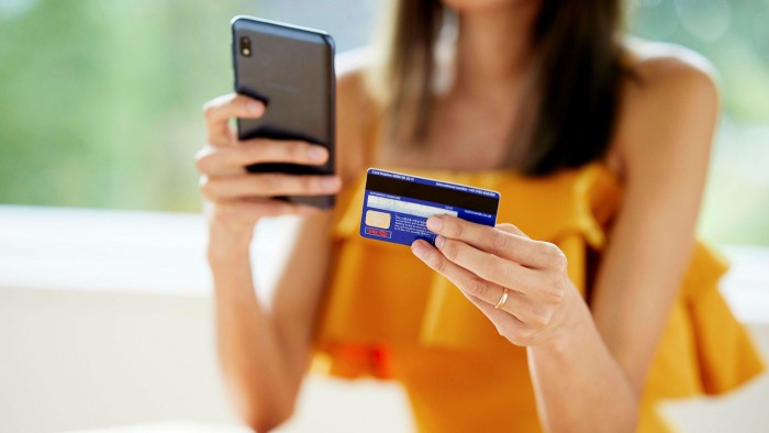 A woman holds a mobile phone in one hand and credit card in another 