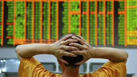 An investor sits in front of an electronic board showing stock information at a brokerage house in Hangzhou