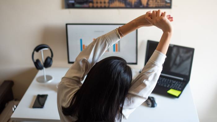Woman stretching while working on computer from a home office