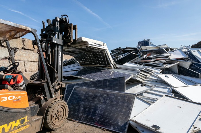 A fork lift truck faces a heap of used solar panels at a facility run by Soren 