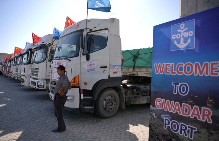 A Chinese worker stands near trucks carrying goods at Gwadar Port