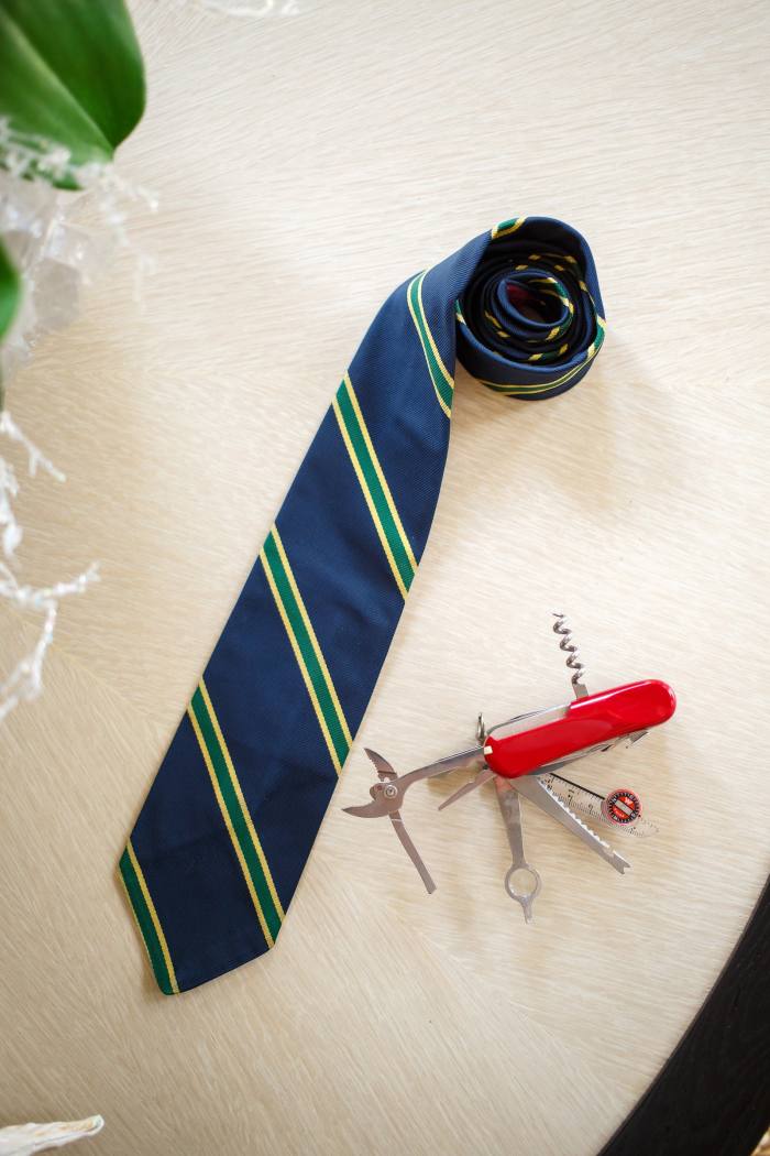 A blue and green striped tie with a red Swiss army knife