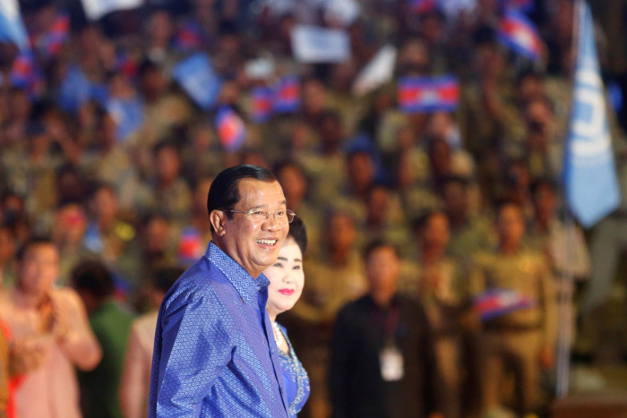 Former Cambodian prime minister Hun Sen smiles as a large crowd looks on