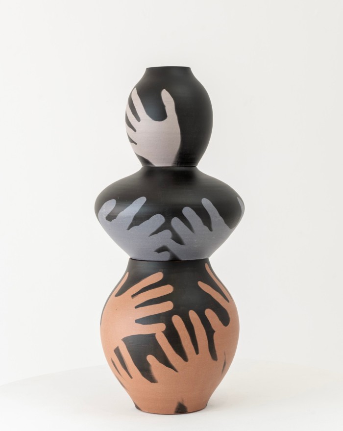 A vase of three rounded shapes with handprints on each level