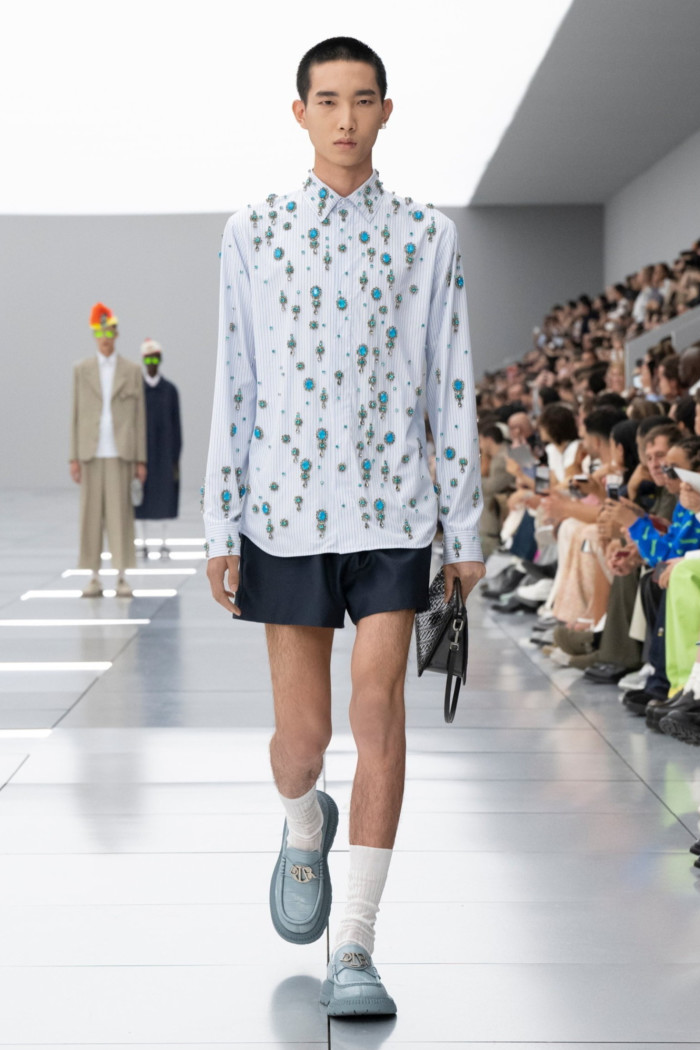 A model on the runway in shorts and white shirt with floral pattern