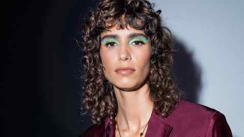 A model backstage wearing green and blue eyeshadow at Versace spring/summer 2022