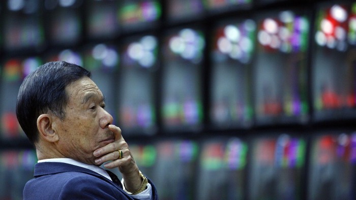 A man looks at banks of stock market monitors