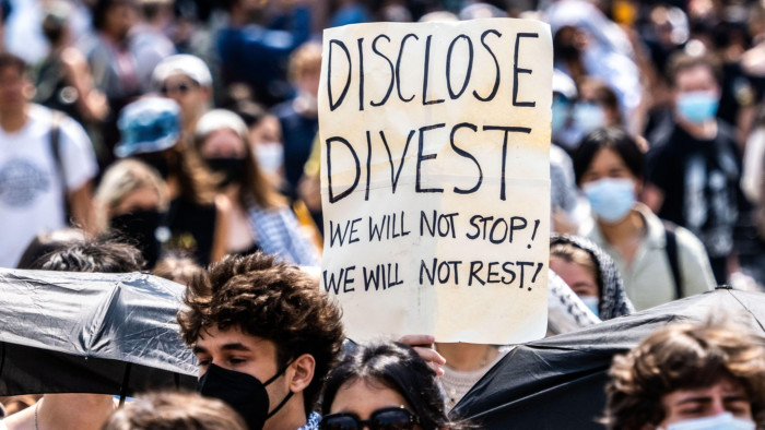 A sign held by a student marching around the Columbia university encampment reads Disclose Divest We will not stop! We will not rest!