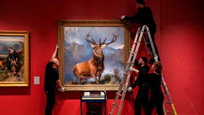 Gallery assistants re-hang a painting of a stag roaming a mountainside