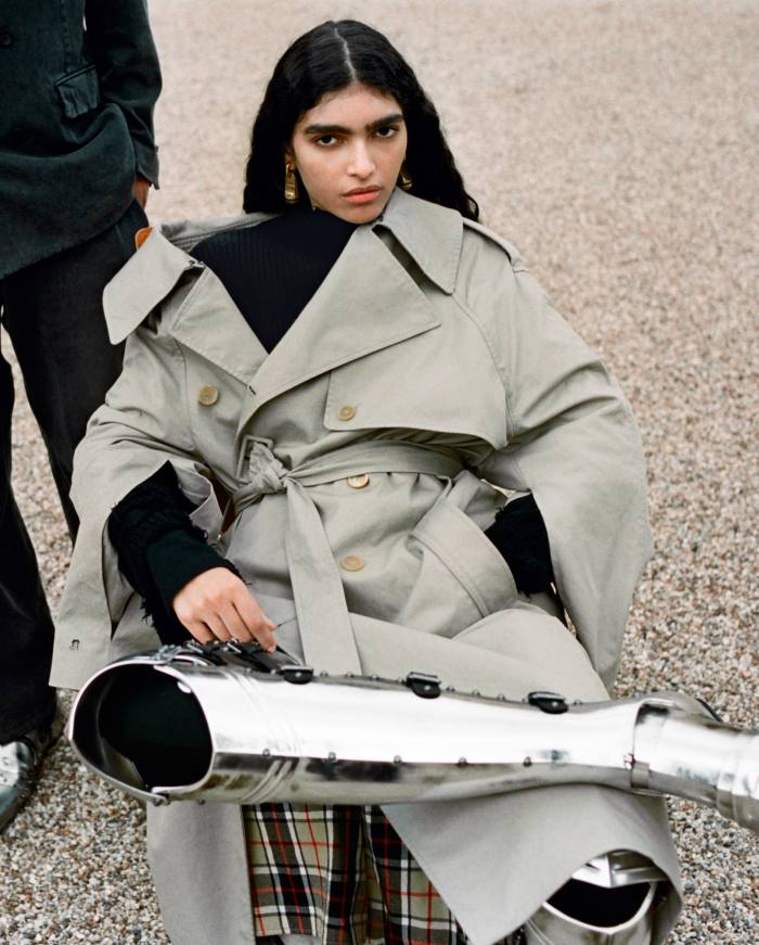 Cotton twill off-shoulder trench coat, £2,290. Cotton-knit destroyed overdyed turtleneck, £1,050. Stretch-tailoring twill five-pocket mini-skirt, £750. Technical-jersey trompe-l’oeil leggings, £450. Chevalier over-the-knee boots, £5,250. Dark aged-gold, aluminium, brass and rubber Hotel earrings, £450. In model’s hand, Mask Butterfly sunglasses, £320. All Balenciaga