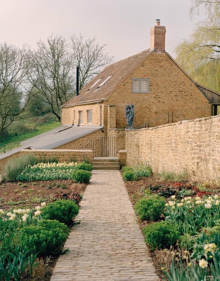 A path through daffodil and tulip beds leading to the Cheese Barn