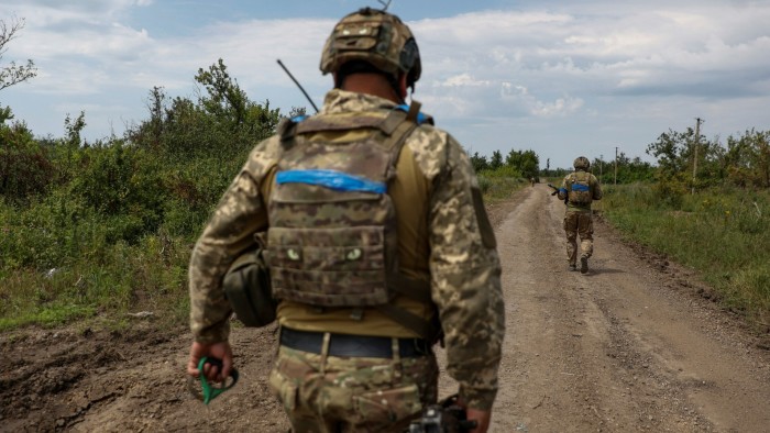 Ukrainian servicemen walk along a road in the country’s Zaporizhzhia region