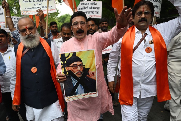 Hindu protesters hold a poster of Gurpatwant Singh Pannun