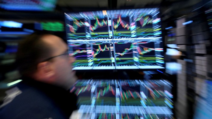 A trader walks past a screen in the New York Stock Exchange