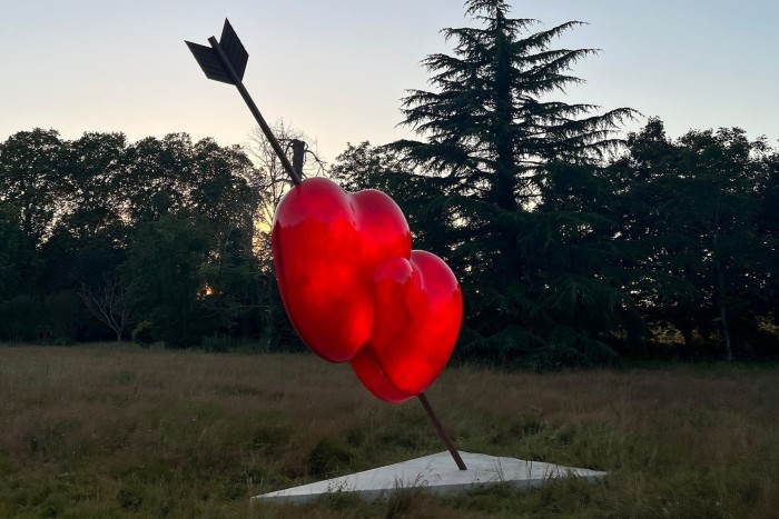 A large sculpture of an arrow piercing two translucent red hearts