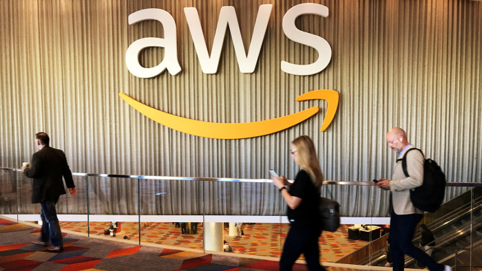 People walking past an Amazon Web Services logo