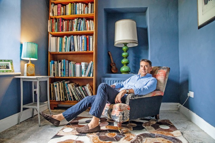 Bill Amberg in his study with the bookcase he designed to complement the Edward Bulmer navy-blue wall