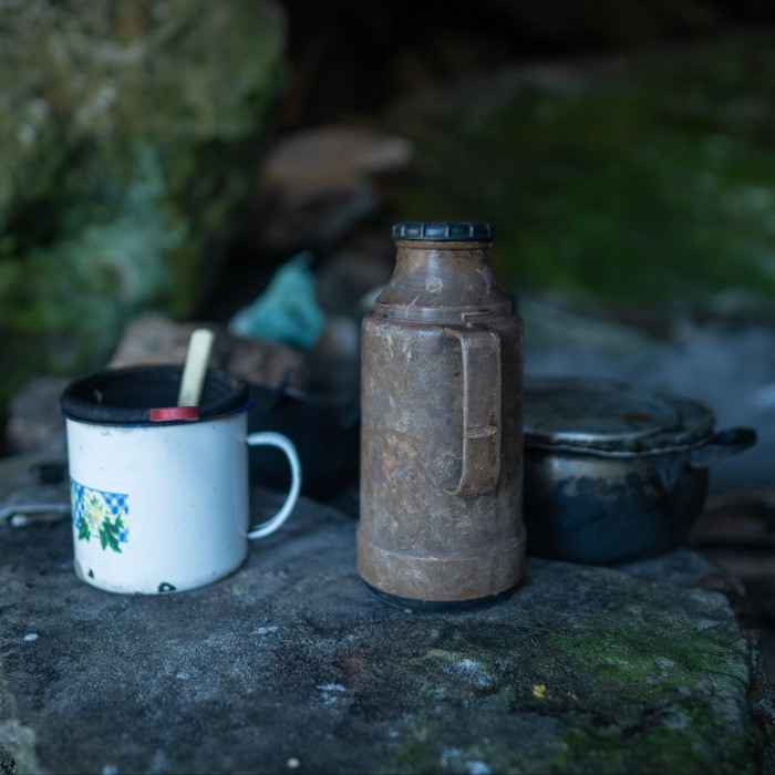 A coffee cup and a flask perched on a rock