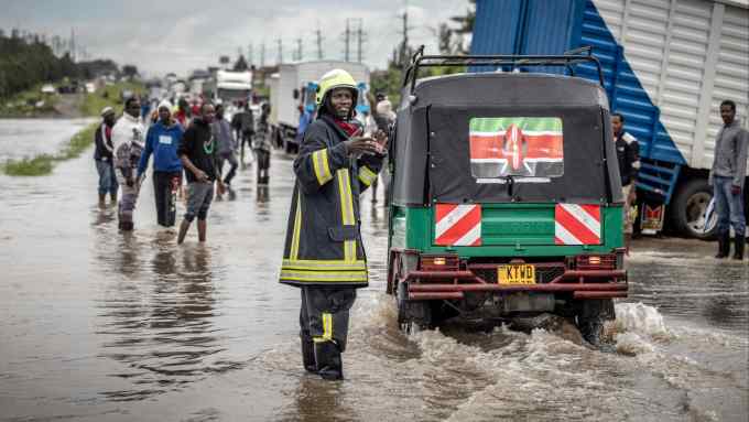 A firefighter gives instructions to commuters on a flood-hit road in Kitengela, Kenya