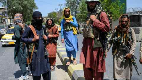 Taliban fighters stand guard along a street near the Zanbaq Square in Kabul on Monday