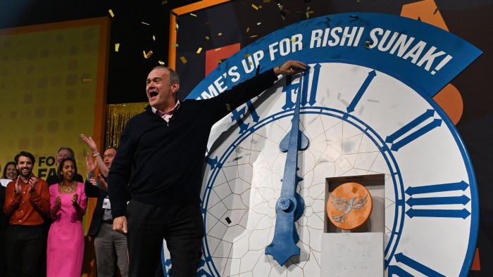 Ed Davey gestures to a clock which says ‘time’s up for Rishi Sunak’