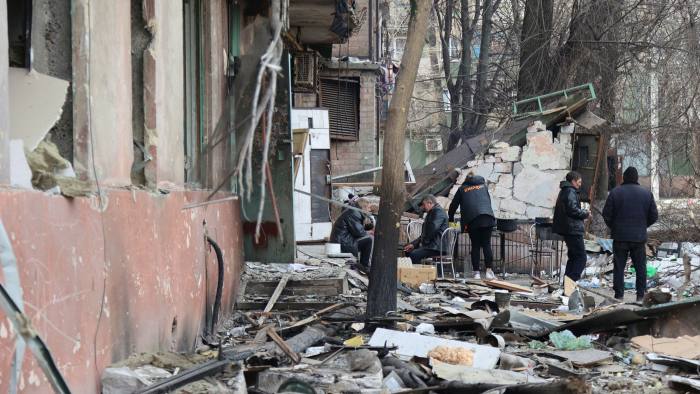 People gather in front of a damaged building in Mariupol