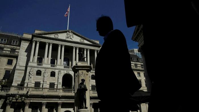 Workers are silhouetted as they walk past the Bank of England in London