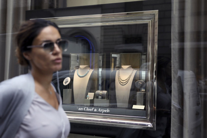 A pedestrian passes a jewelry display in the window of a Van Cleef & Arpels luxury goods store