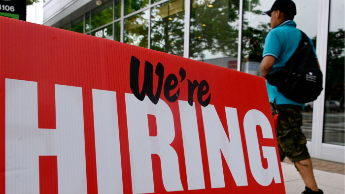 a man walks past a ‘now hiring’ sign posted outside of a restaurant in Arlington, Virginia