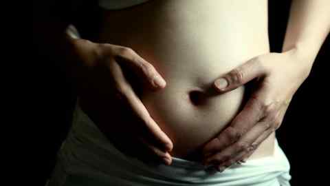 A pregnant woman holds her hands on her belly
