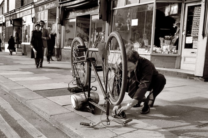 A man fixes a puncture on his bike on Liverpool Road, Peel Green, Eccles, Greater Manchester, circa 1978.