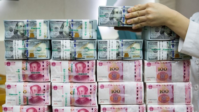 A KEB Hana Bank employee arranges bundles of US one-hundred dollar banknotes and Chinese one-hundred yuan