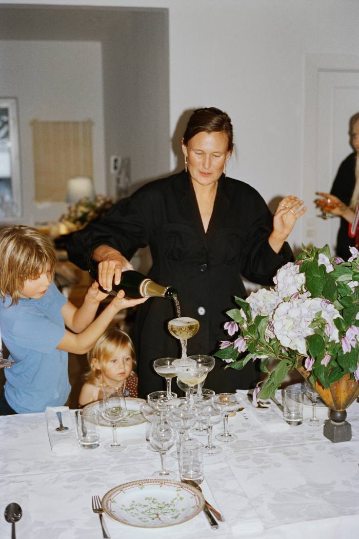 Sophie Bille Brahe pours a champagne tower, watched by her children Beate and Johan. Picture at top: Sophie and her brother (on her left) sharing a toast with (bottom left) their mother Elisabeth Bille Brahe, (head of table) Sophie’s boyfriend Jeppe Juel Møller, (on Sophie’s right) Frederik’s wife Caroline Bille Brahe and friends, before beginning their meal with pumpkin soup and truffle whipped cream