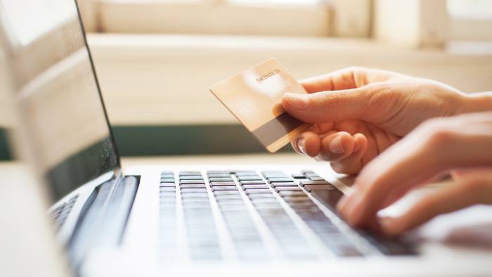 A view of a person’s hand holding a credit card while doing online shopping