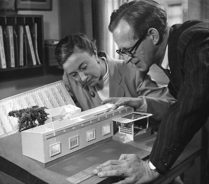 A man and a woman examine an architect’s model of a small school