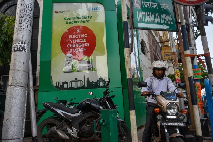 An EV charging station with a man on a moped