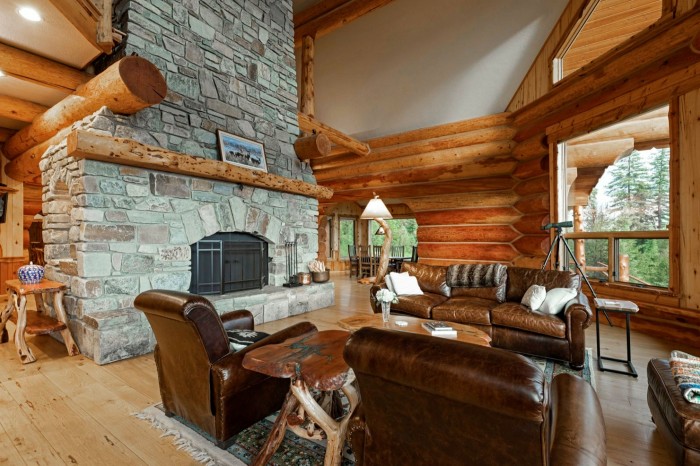 The interior of a log house with a stone fireplace and wood floors