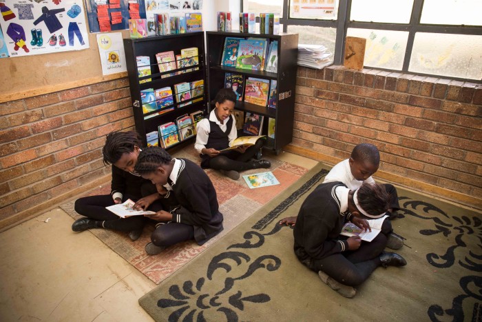 Students sitting on the floor reading independently or with a classmate