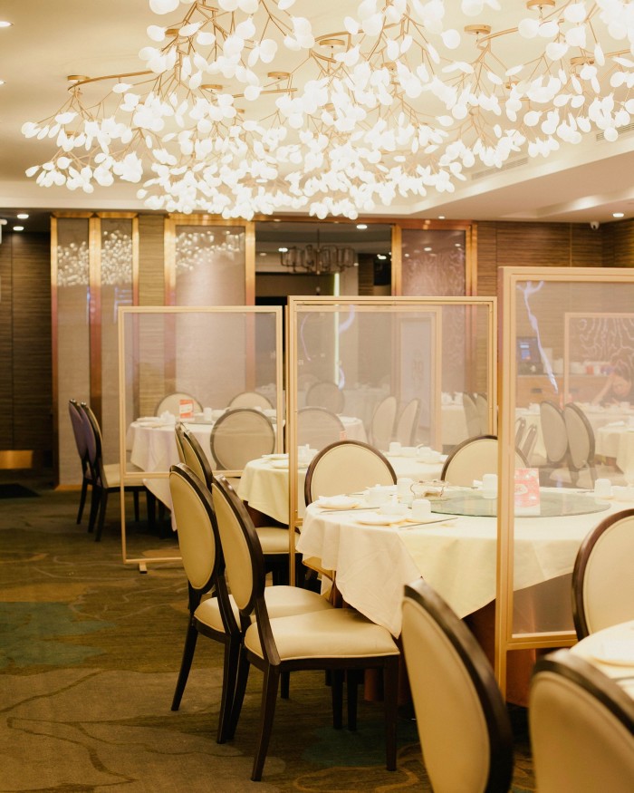 Tables and chairs beneath a chandelier in the shape of branches at Chef’s Choice Chinese Cuisine