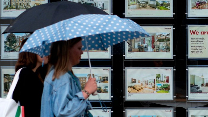 People walk past an estate agents in London