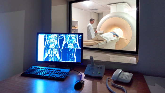 A doctor monitors a CAT scan procedure