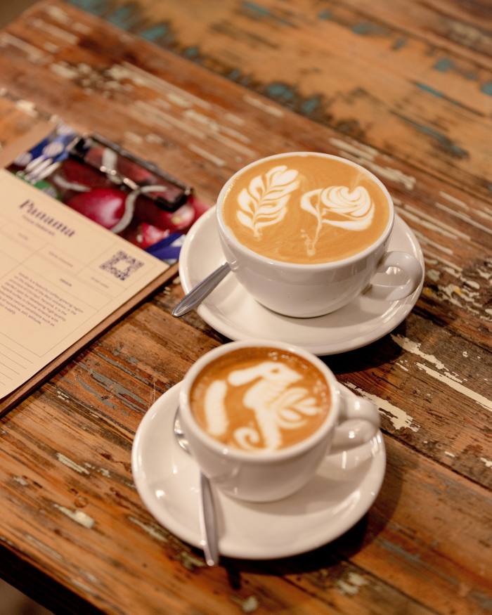 Coffee art depicting a seahorse and flowers atop a flat white and an espresso at Manchester Press 