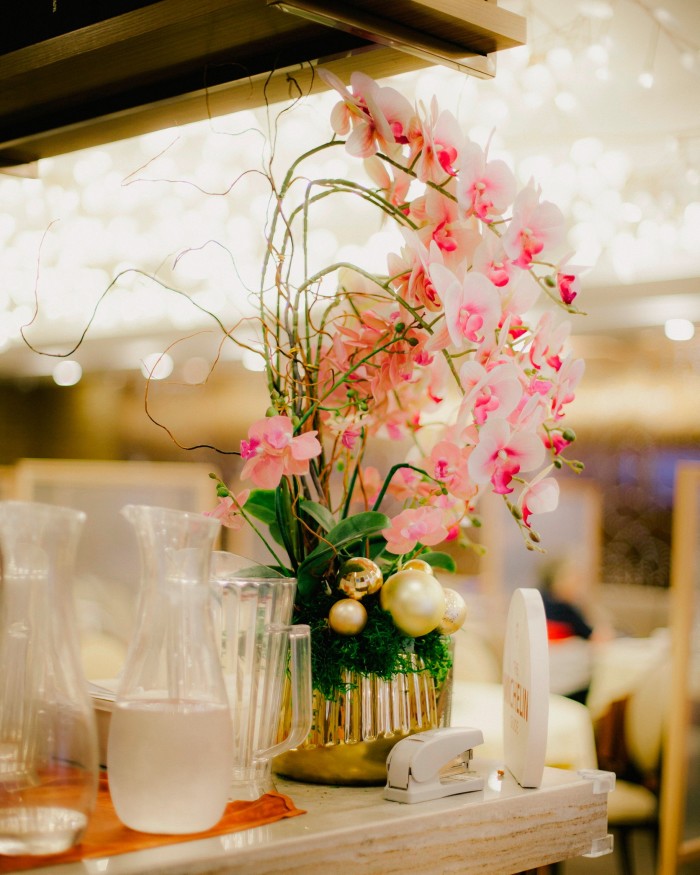 Pink and red blossoms in a gold vase on a counter Chef’s Choice Chinese Cuisine