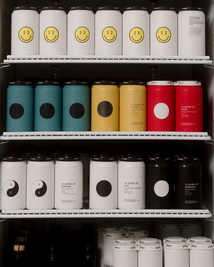Shelves of white, black, blue, yellow and red cans of beer at 33 Acres Brewing Company