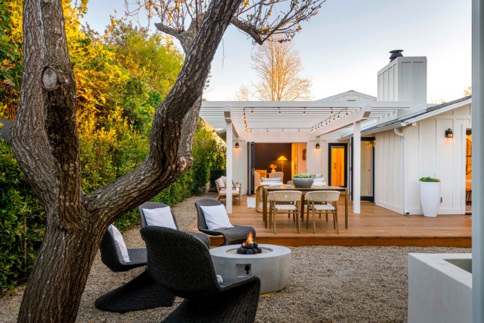 A white coastal-style bungalow with a sheltered decked area and tall hedges, $3.995mn