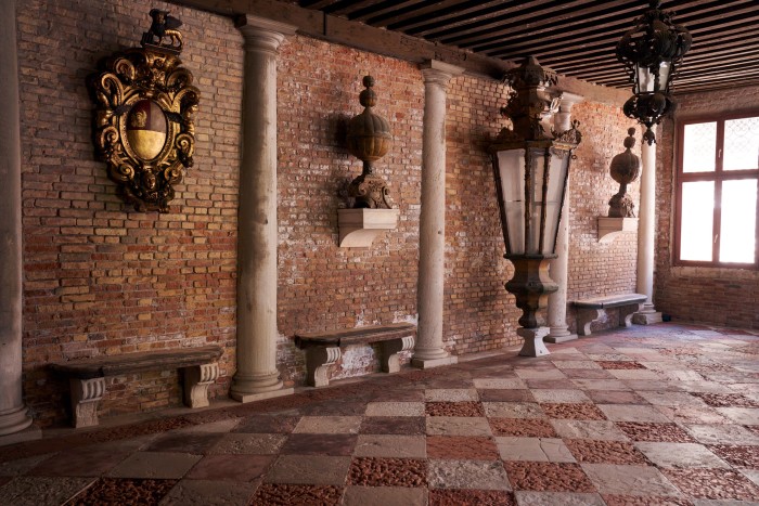 The entrance hall of his home, with a wooden coat of arms (left) and a lantern from a Venetian galleo