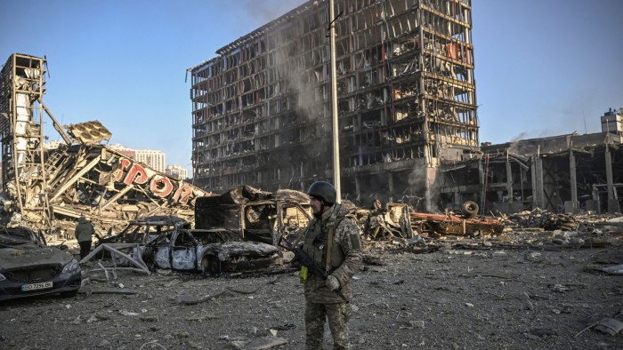 A Ukranian serviceman walks between debris of Retroville shopping mall and residential district after a Russian attack in Kyiv