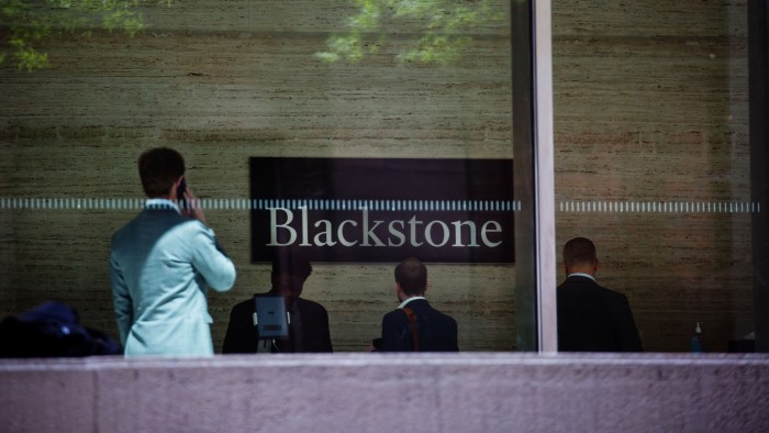 People walk around a Blackstone sign