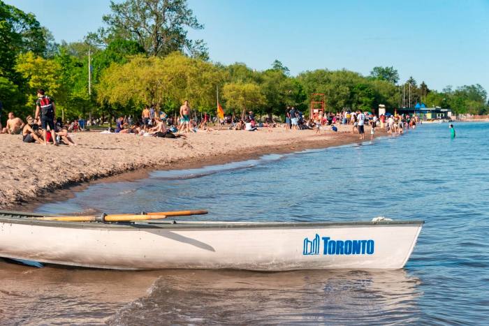 Small boat with Toronto city logo by a beach on Toronto ISlands