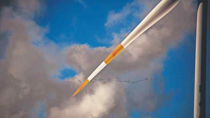 Migrating wild geese fly past the blade of a wind turbine